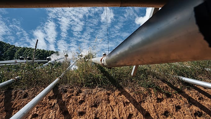 Condensing pipes running down an embankment against an open sky