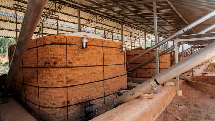 Row of brick carbonisation kilns under a steel roof at a production site