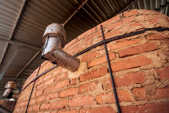 Brick kiln wall with a metal condensing outlet under a steel roof